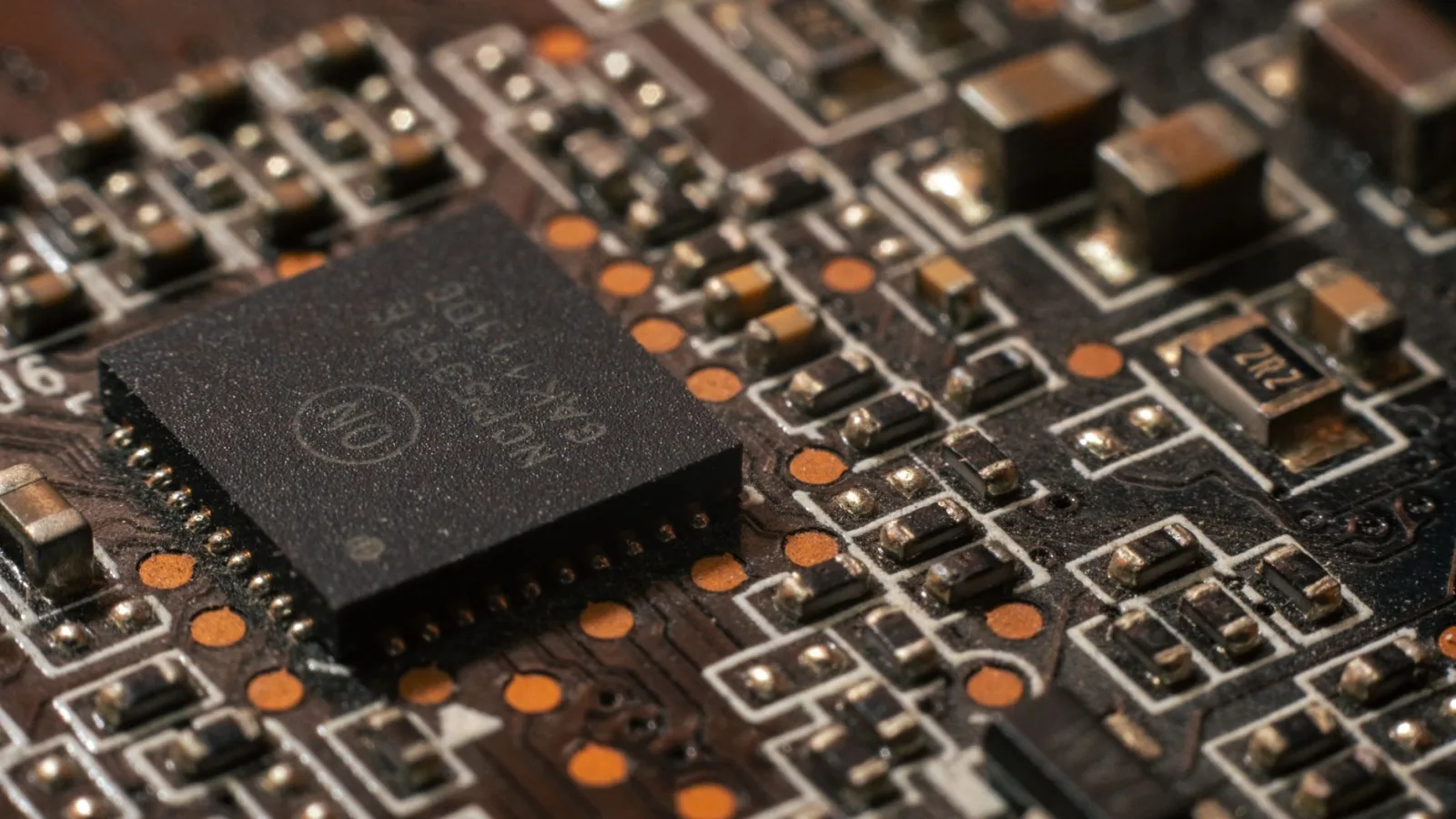 Gros plan sur une puce électronique soudée sur une carte mère, symbole de l'investissement dans la tech